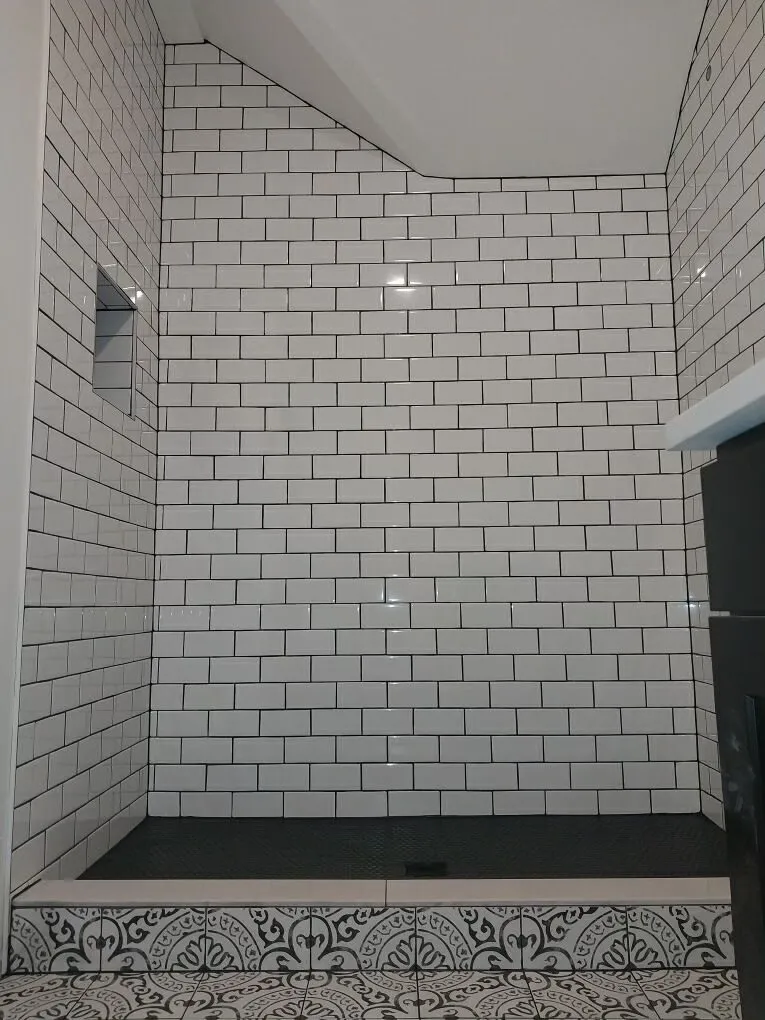 White subway-tile shower with a patterned tile border at the base