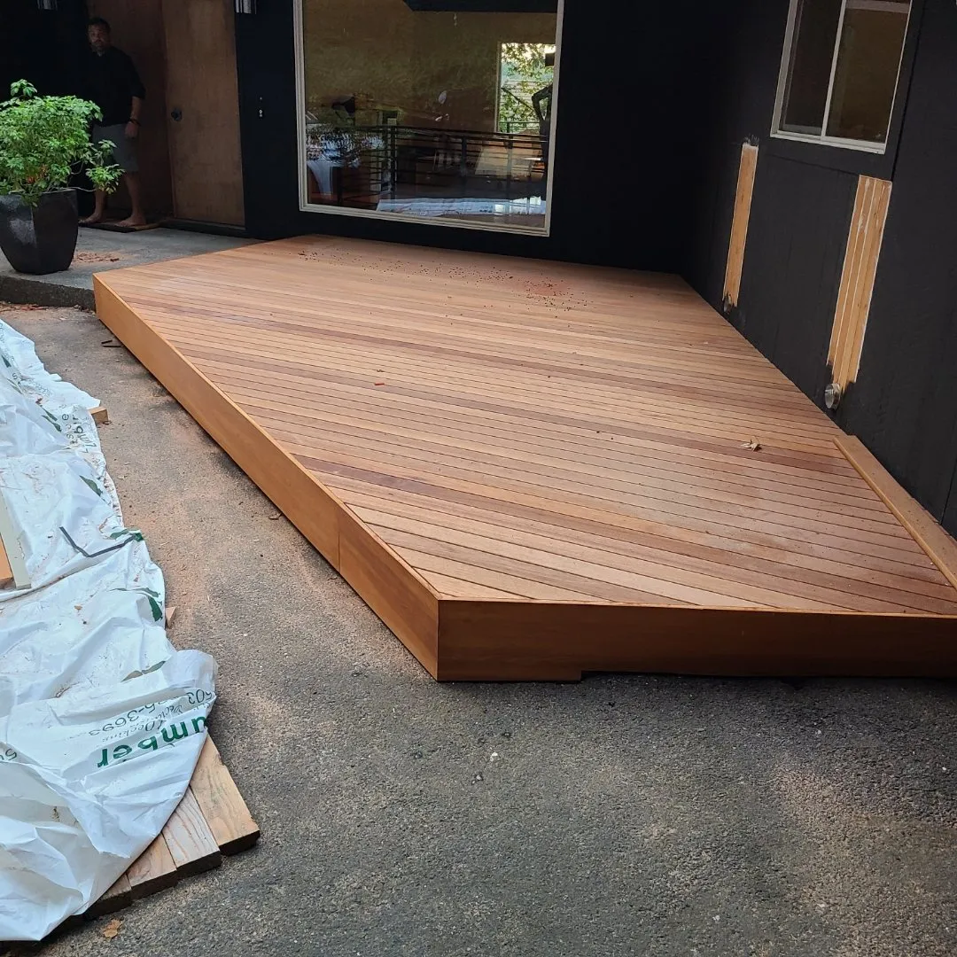 Finished wood deck beside a dark-sided house