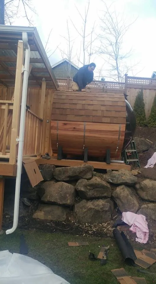 Barrel sauna under a roof on a raised platform