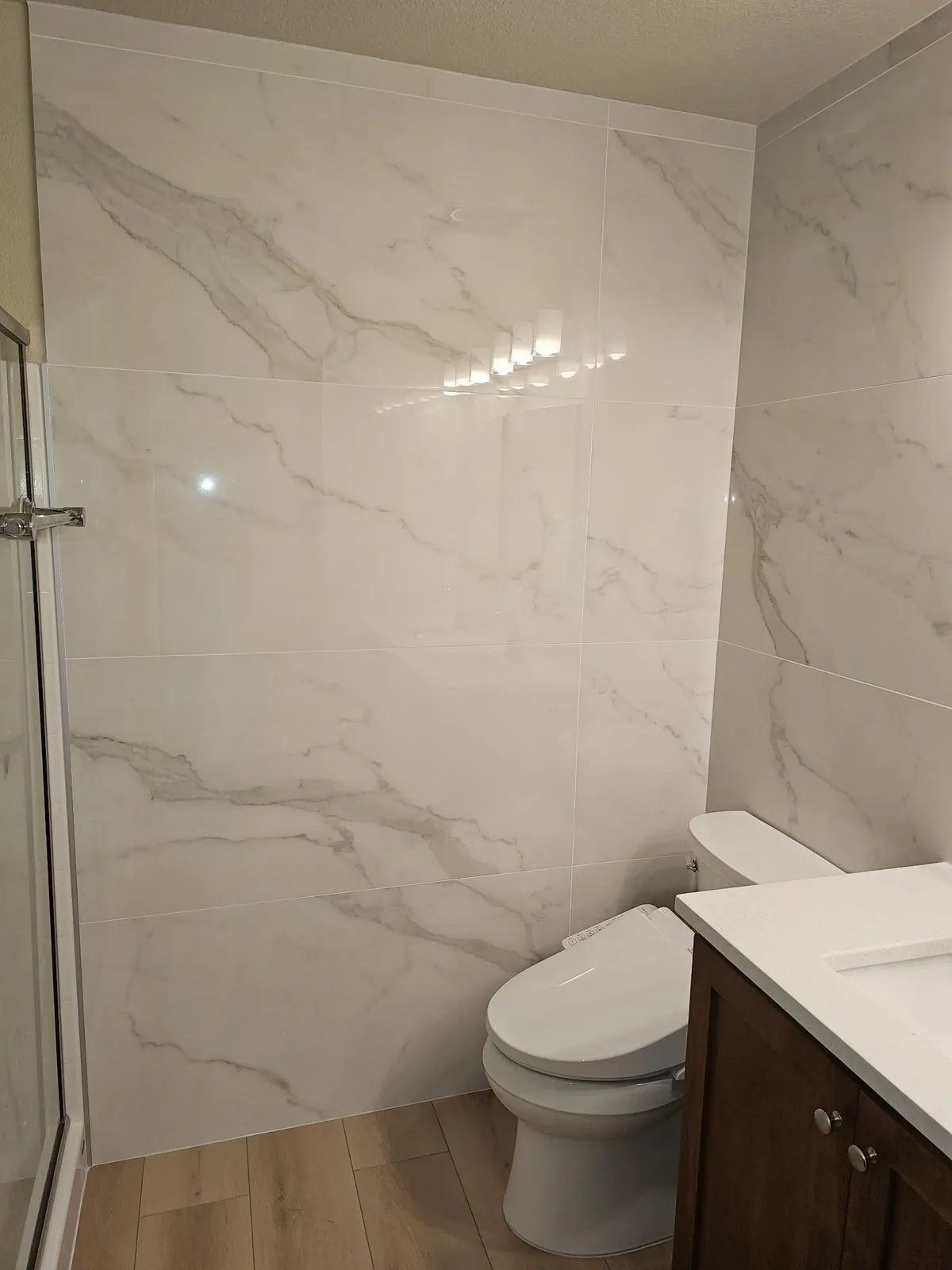 Marble-look bathroom walls beside the toilet and vanity