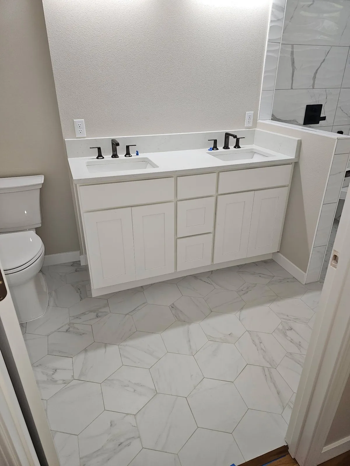 Double white vanity with black fixtures on hexagon floor tile
