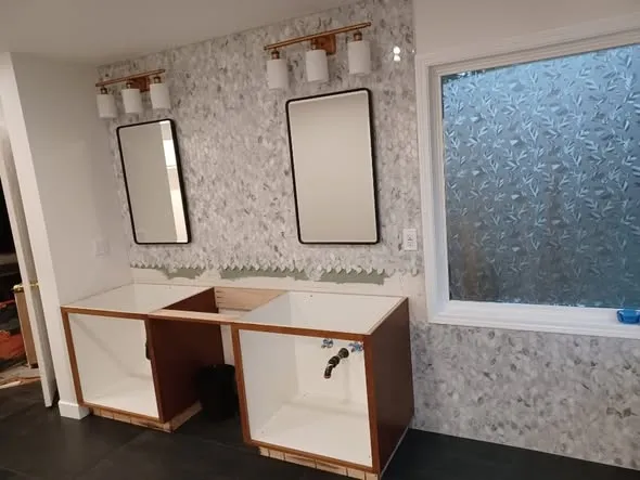 Double vanity with marble mosaic backsplash and black mirrors