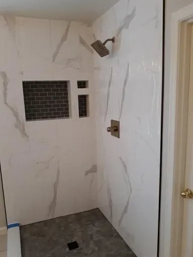 Marble-look shower with a recessed niche and dark mosaic insert