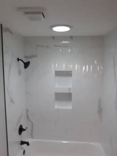 Tub and shower with black fixtures and a built-in shelf niche