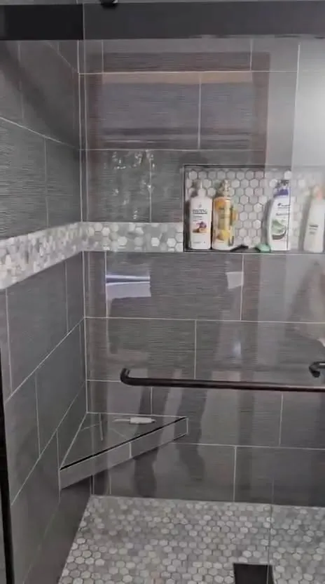 Charcoal tile shower with niche and pebble mosaic floor