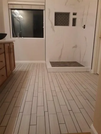 Marble-look shower beside a wood-look plank floor