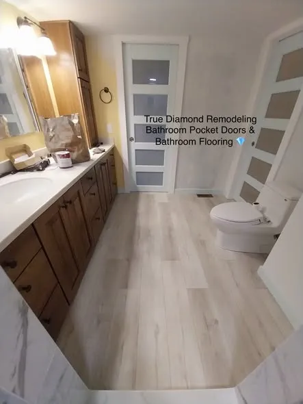 Bathroom with frosted pocket doors and new wood-look flooring