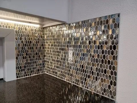 Metallic hexagon mosaic backsplash lit by under-cabinet lights